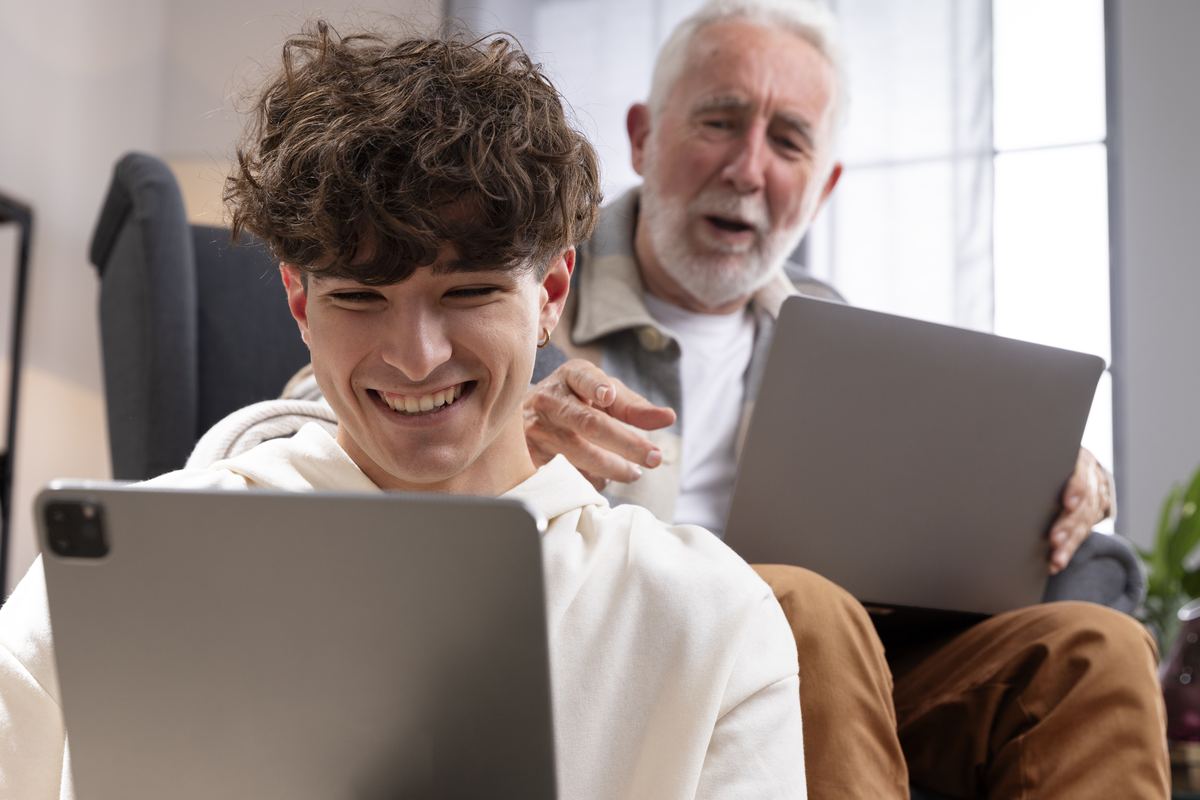 Grandfather and grandson smiling while using laptops together